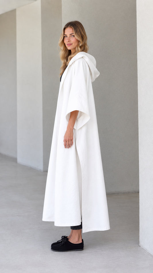 Side profile view of model wearing white hooded canvas cape duster